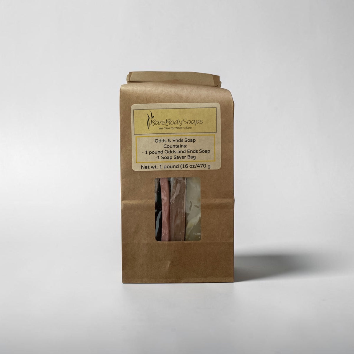 A brown kraft paper bag package of Some Bodies Soaps Odds & Ends Soap Countenance, featuring a clear window showing several bars of soap inside, set against a plain light gray background.