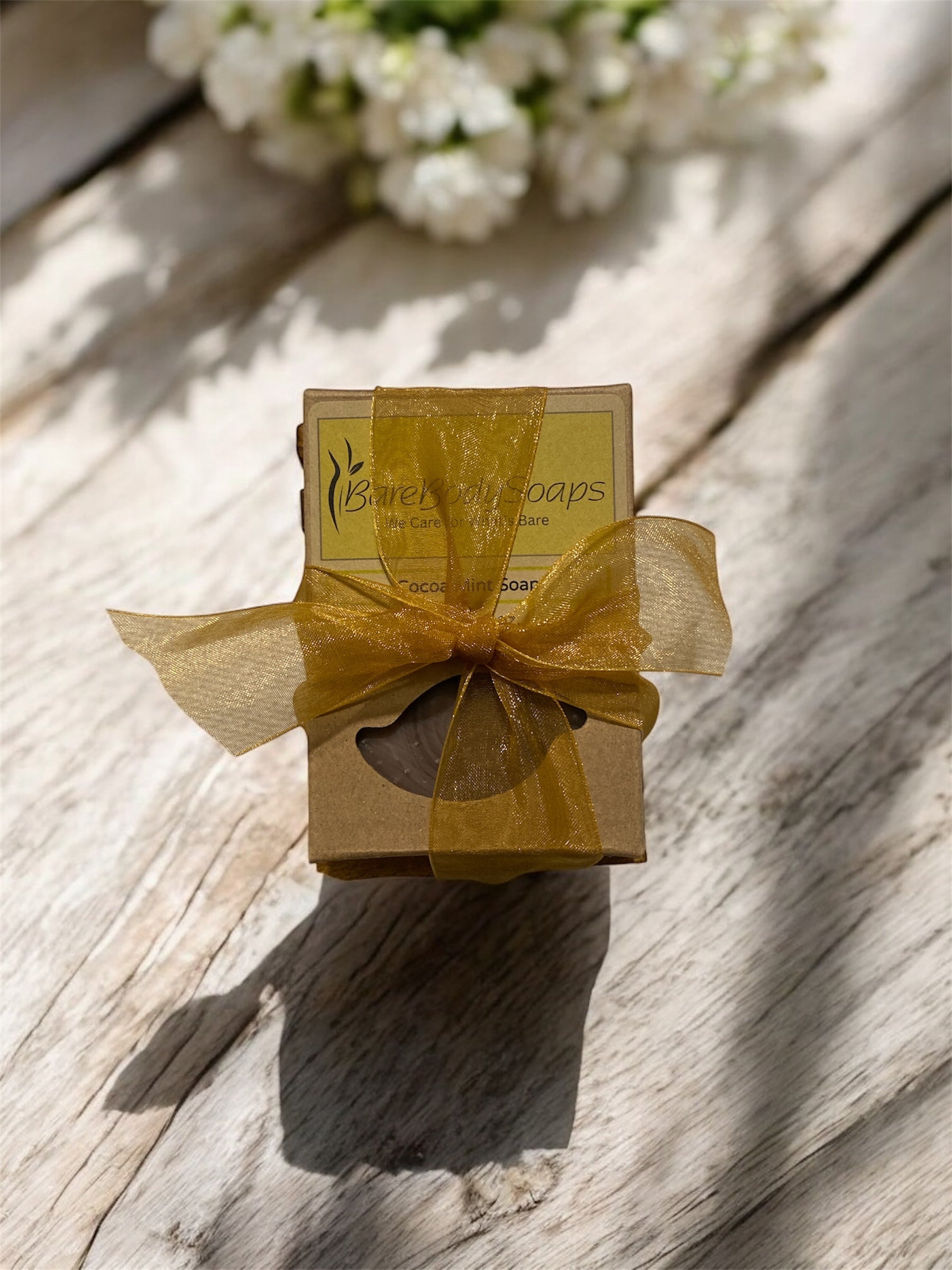 Bar of soap in a decorative box with a yellow bow on a wooden soap dish